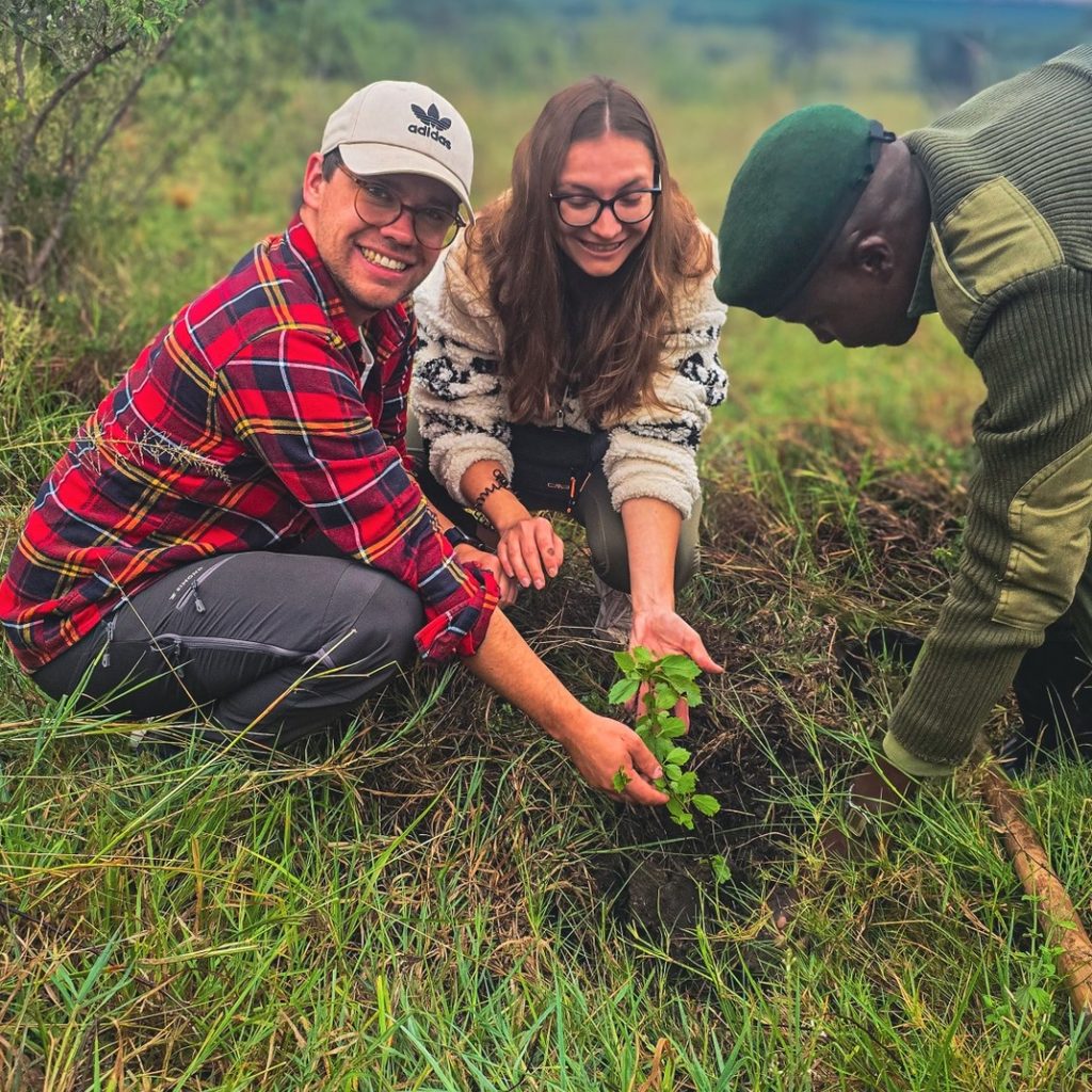 Safari guests and ranger planting a tree for conservation guided by female safari guide initiatives