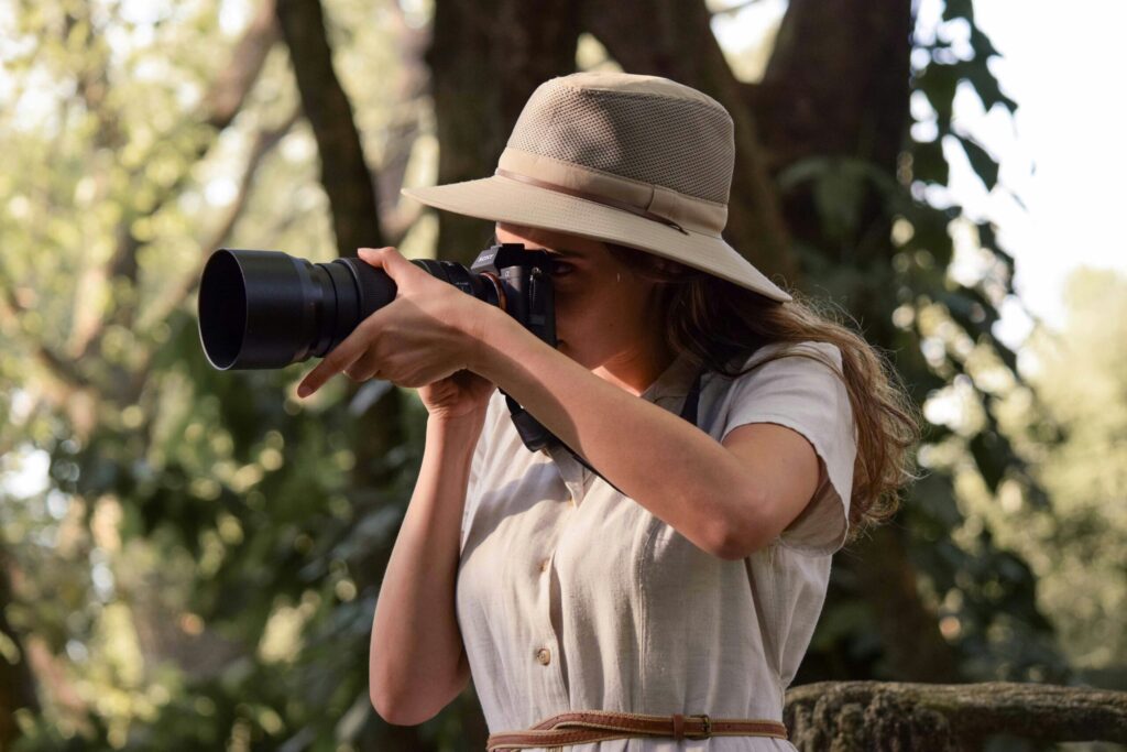 Solo female traveler wearing neutral safari clothing and hat taking photos on a solo female safari Kenya trip.