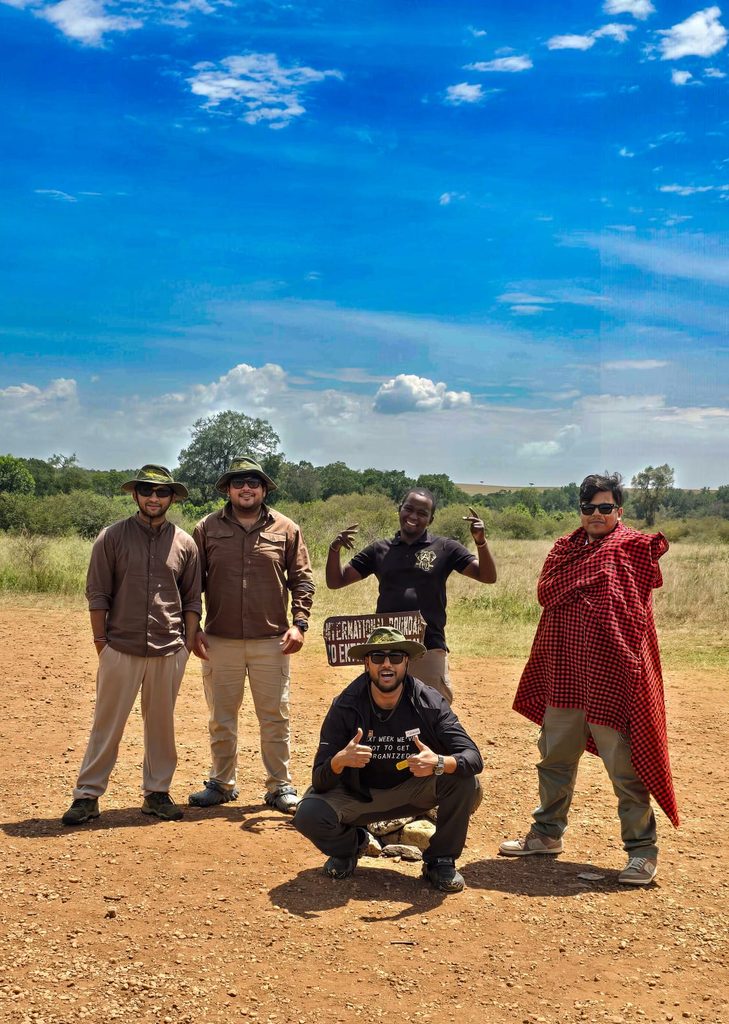 Small group travellers posing at the Kenya border pillar on a book a seat safari Kenya